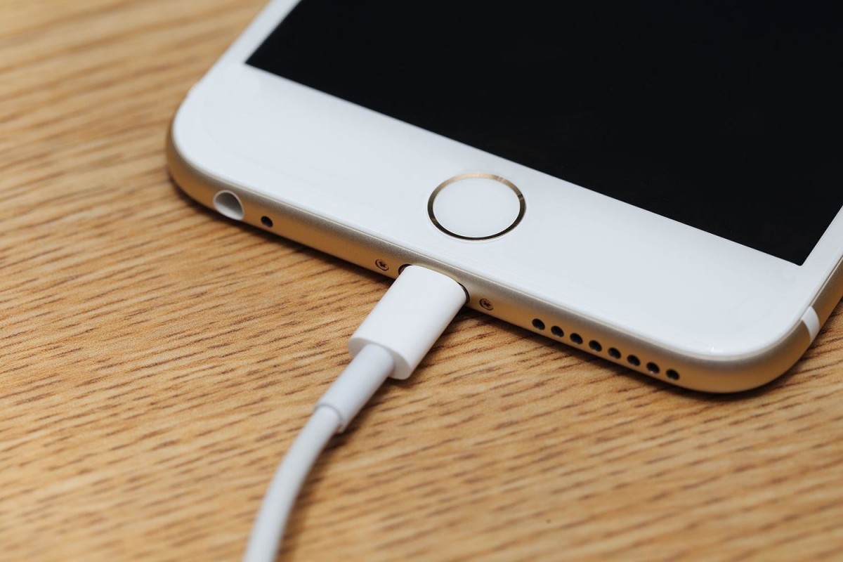 iPhone di atas meja, sedang dalam proses charging.